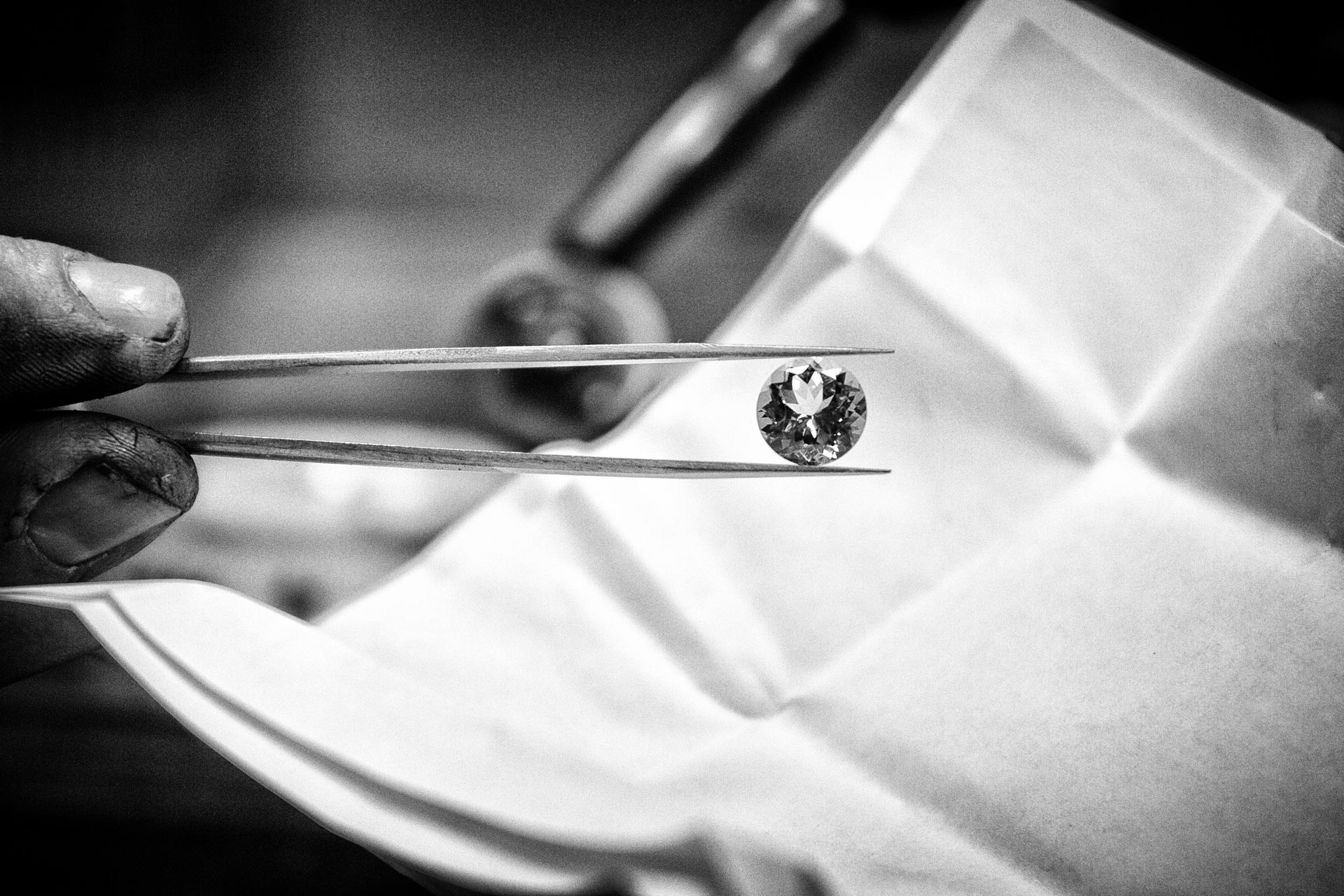Wouter Dijkman houdt een diamant vast met een pincet – zwart-wit close-up van het sieradenambacht.

