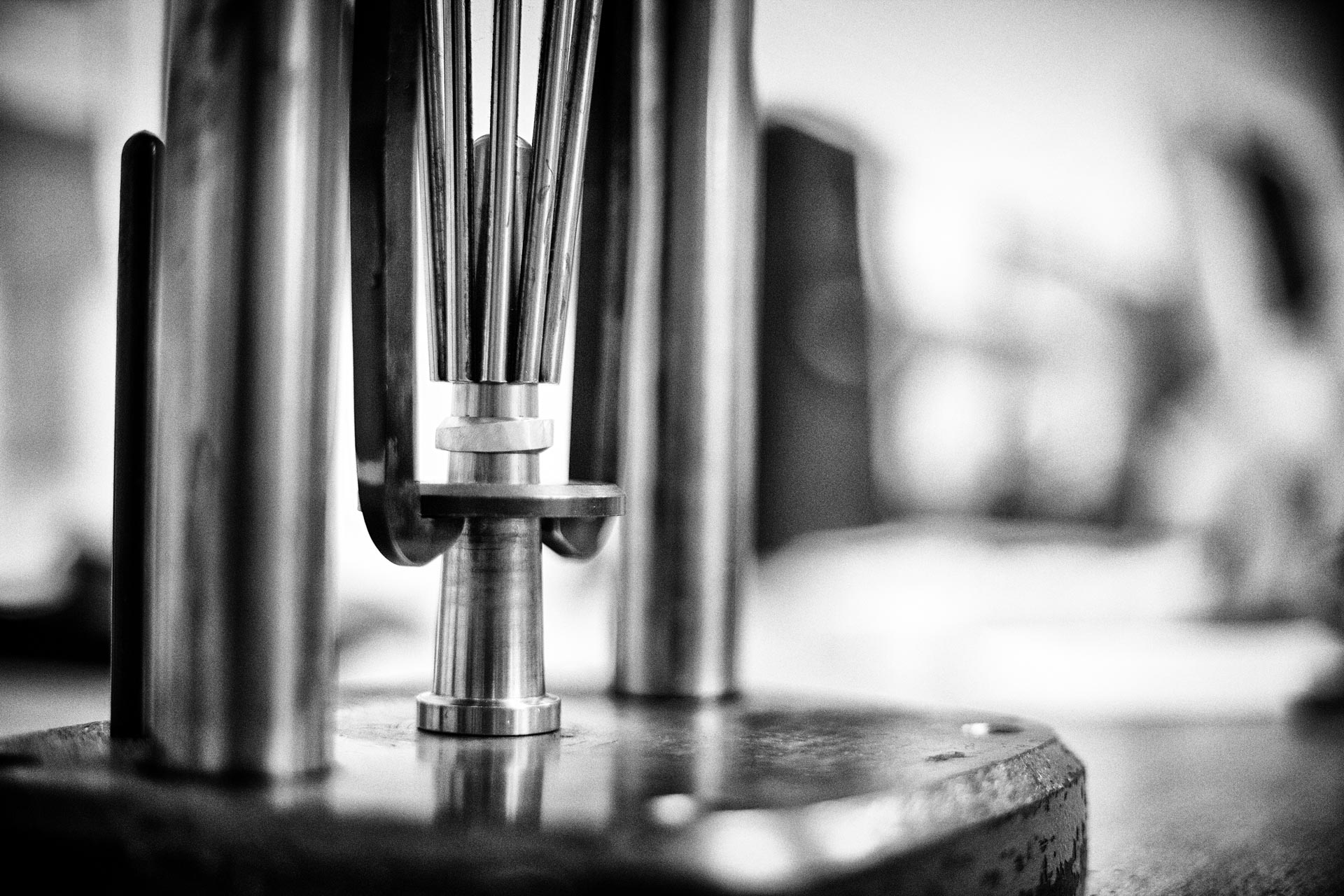 Close-up van een ringvergrotingsapparaat met een gouden ring – zwart-witfoto van het ambacht bij Metal Art Sieraden.

