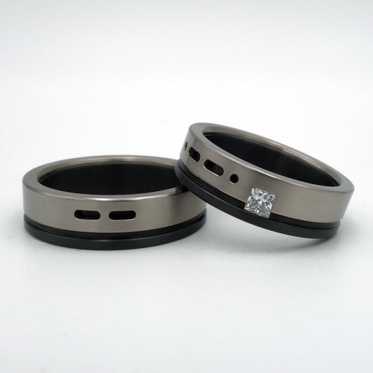 B&W Morse ringenset van titanium en zirkonium – moderne set met grafisch lijnenspel en prinsesgeslepen diamant in de damesring.


