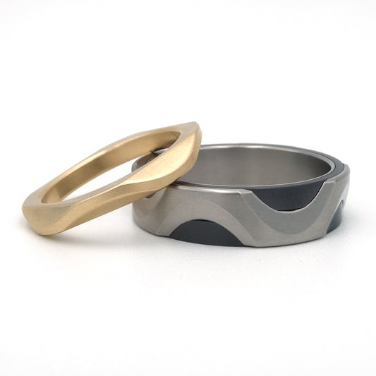 Set trouwringen in titanium, zirkonium en 14k goud met geometrische Rhino-structuur en vloeiende lijnen

